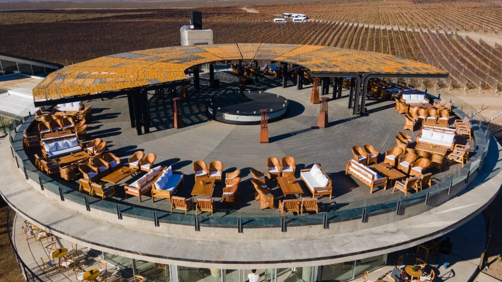 Vista aérea do rooftop circular de uma bodega com lounges e vinhedos ao redor