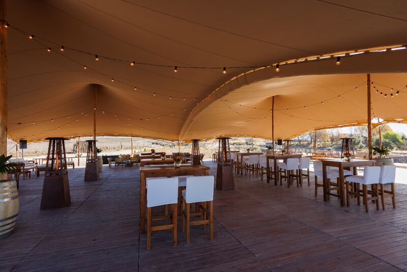 Salão com tenda em tons âmbar montado para celebração